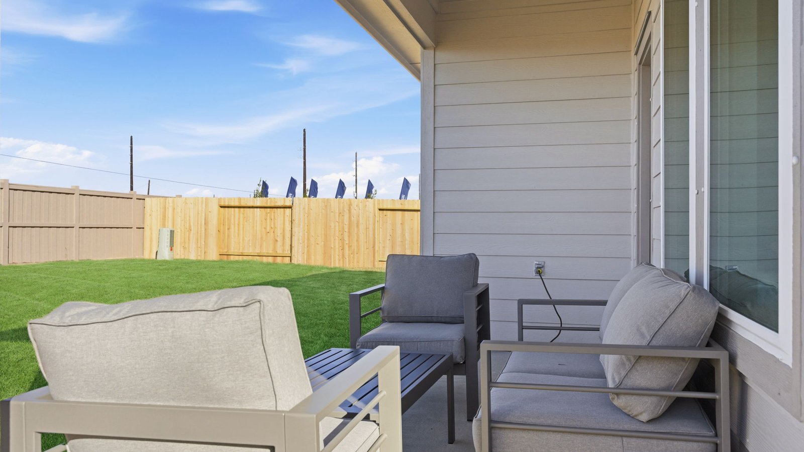 Outdoor covered patio with seating area overlooking a well-maintained lawn, perfect for relaxation.