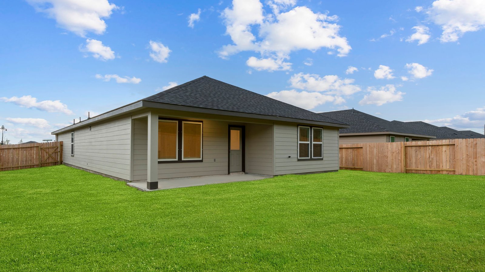 Outdoor covered patio with seating area overlooking a well-maintained lawn, perfect for relaxation.