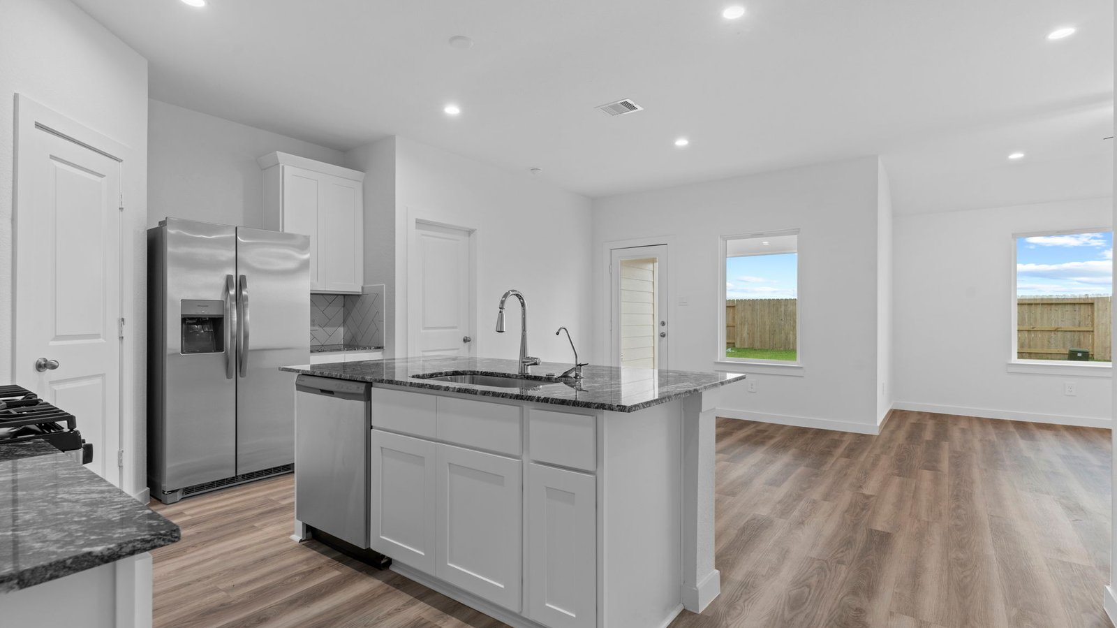 An open concept kitchen with an island with bar seating and access to the living and dining areas.