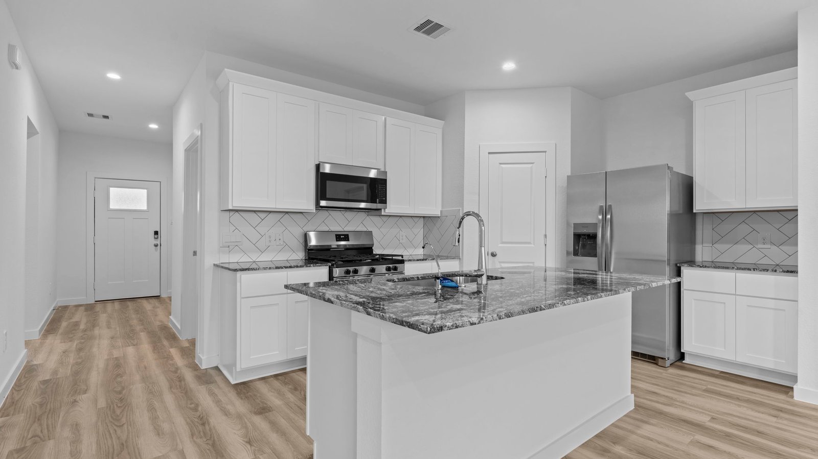 Bright and spacious kitchen with quartz countertops, stainless steel appliances, and an island with bar seating.