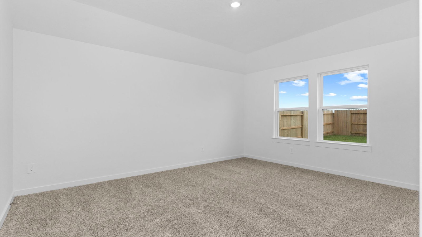Primary bedroom with ceiling fan, plush carpeting, and a large walk-in closet.