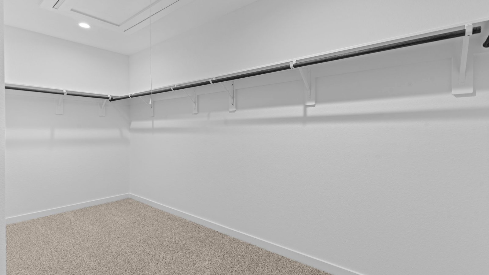 A spacious walk-in closet off the primary bathroom with multiple hanging rods, and shelves for maximum storage capabilities.