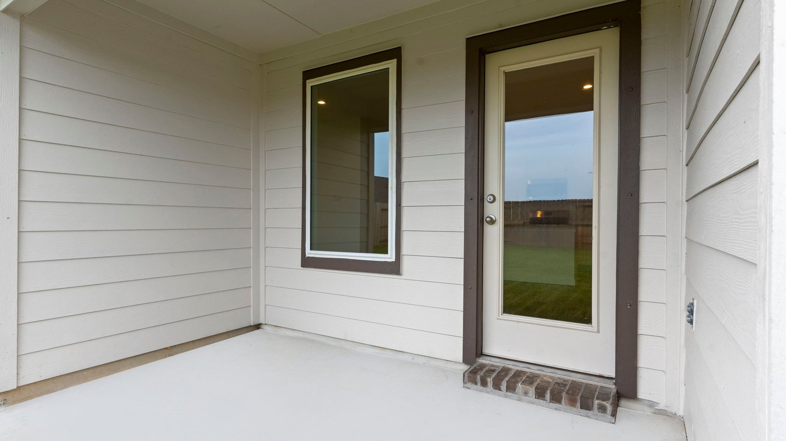 Outdoor covered patio with seating area overlooking a well-maintained lawn, perfect for relaxation.