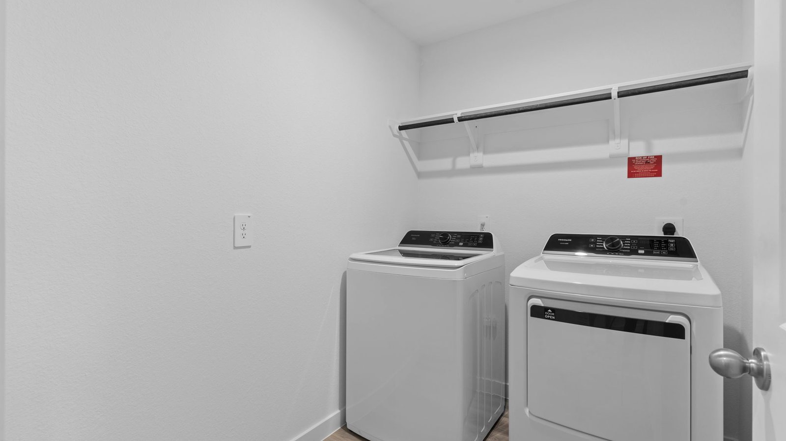 A laundry room featuring a washer and dryer, neatly arranged with ample space for laundry tasks and storage.