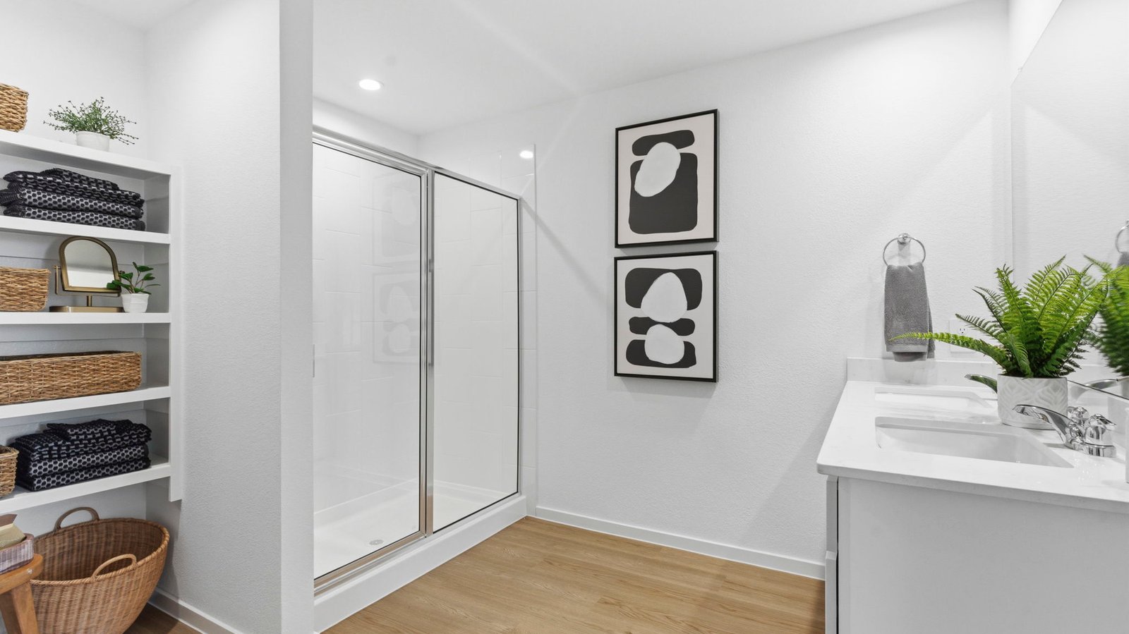 Modern primary bathroom with double vanities, quartz countertops, and a glass-enclosed shower with a walk-in closet.
