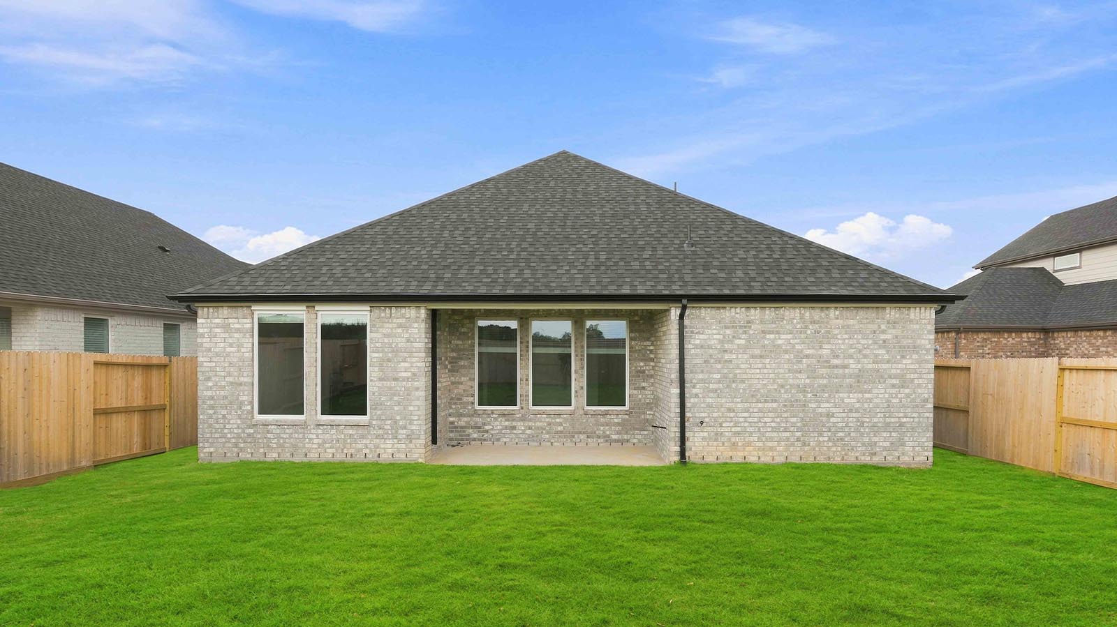Outdoor covered patio with seating area overlooking a well-maintained lawn, perfect for relaxation.