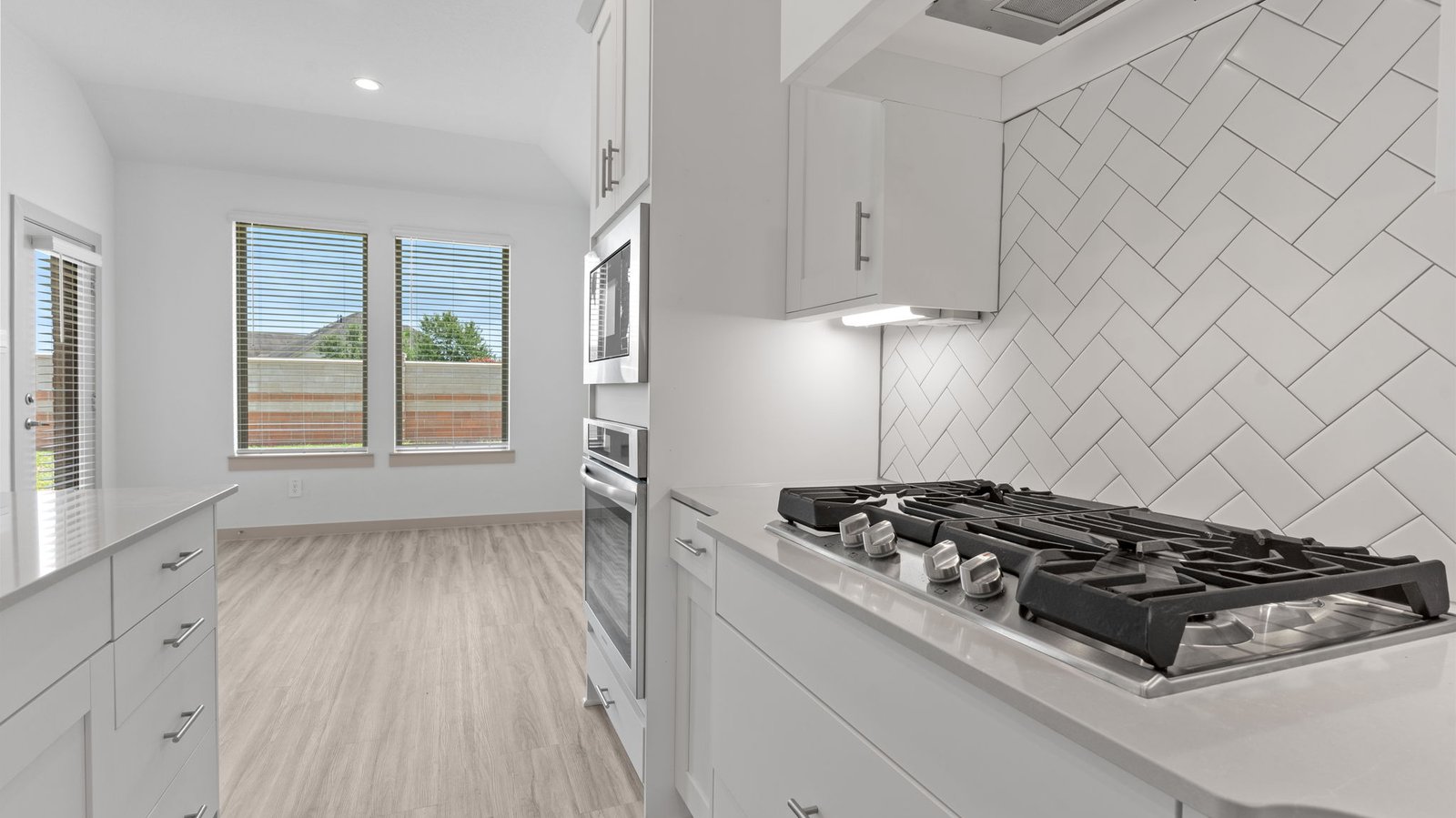 Kitchen view of the breakfast/dining area with two windows and a glass back door.