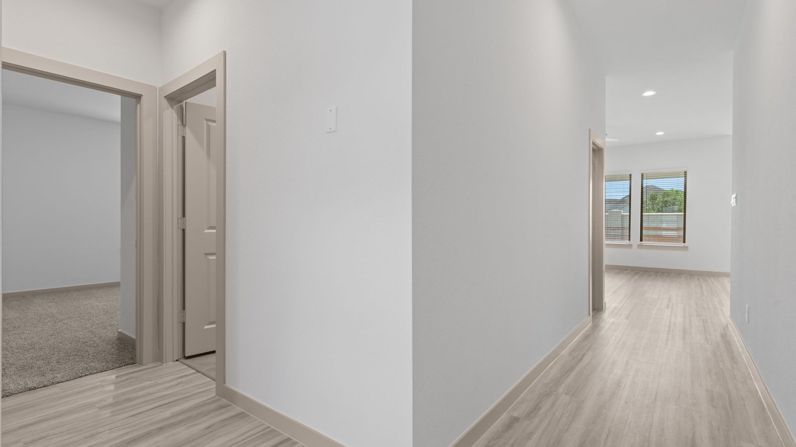 Hall view of the laundry room, bedroom. and the family room.