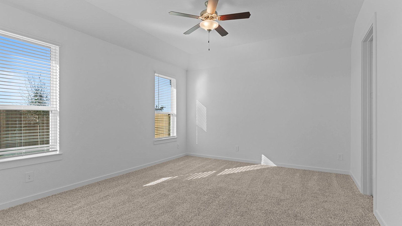 A spacious primary bedroom emphasizing open space and natural lighting with large windows.