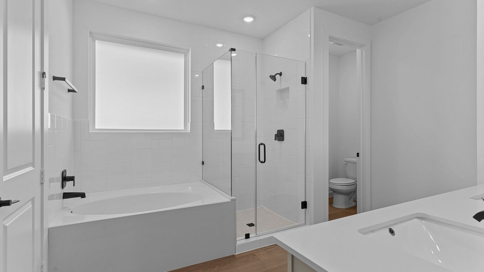 Luxurious primary bathroom with dual vanities, a soaking tub, glass-enclosed shower and walk-in closet.