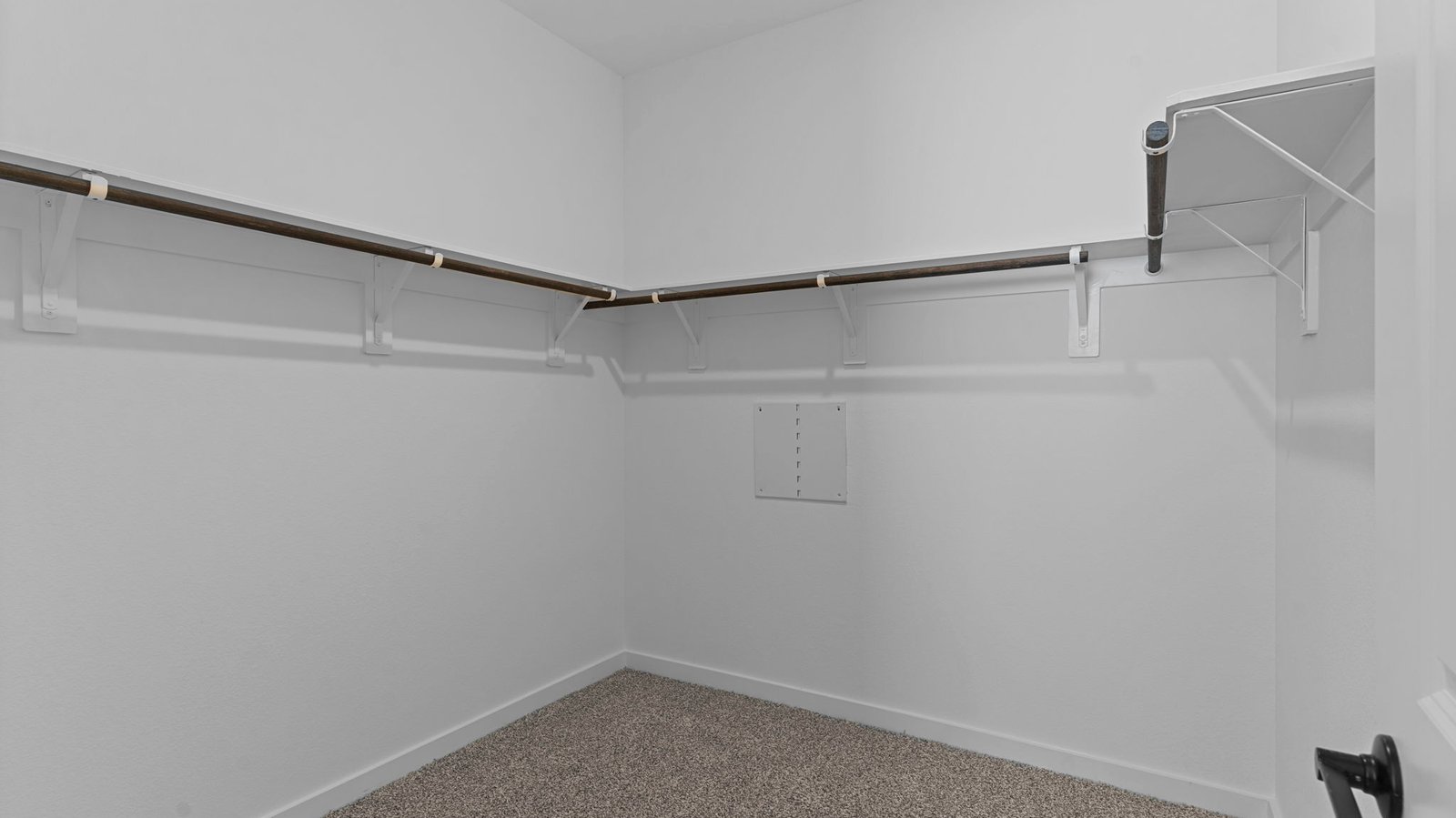 A spacious walk-in closet off the primary bathroom with multiple hanging rods, and shelves for maximum storage capabilities.