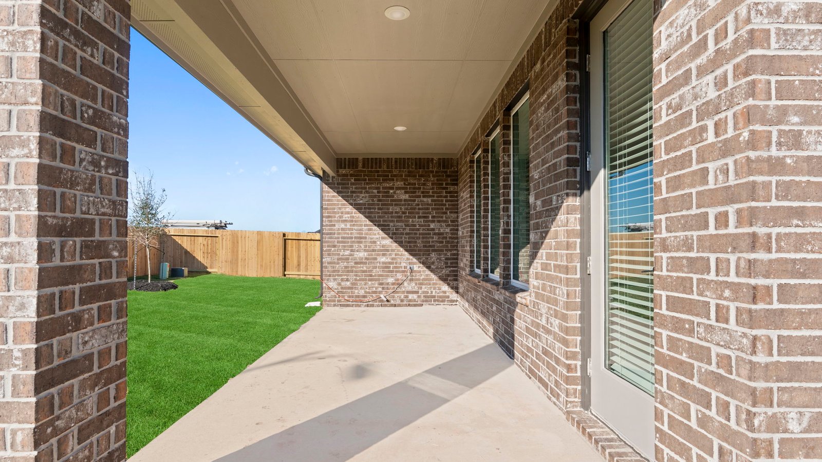 Outdoor covered patio with seating area overlooking a well-maintained lawn, perfect for relaxation.