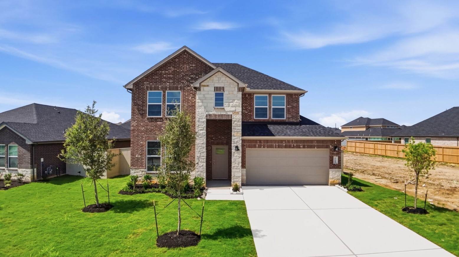 A two-story home with brick and stone exterior with a two-car garage and a well-maintained front lawn in league city