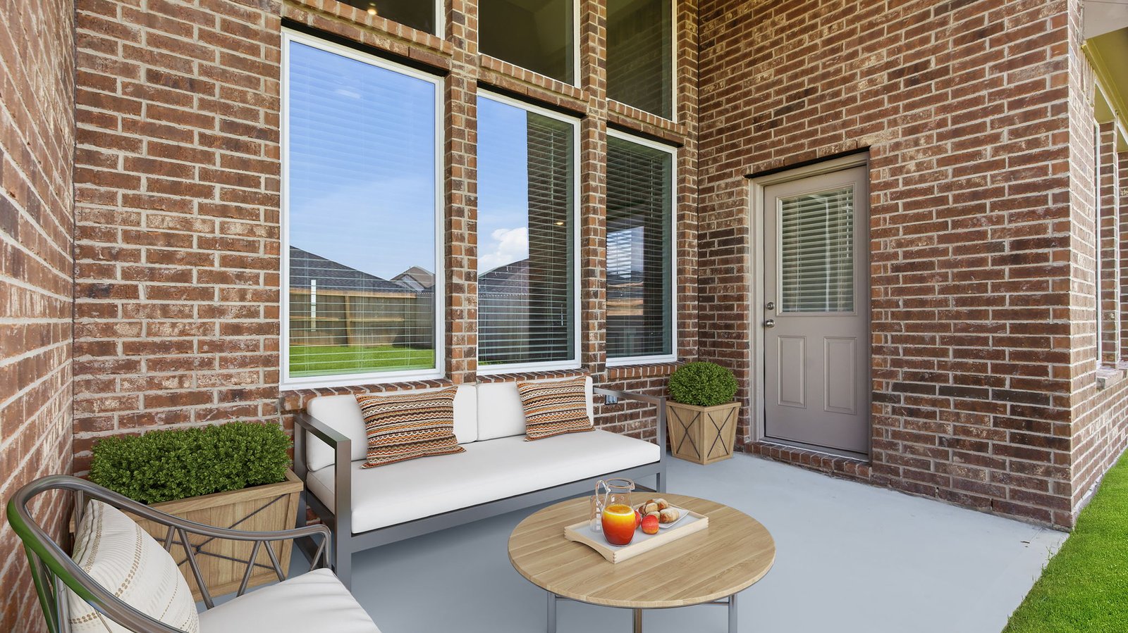 Outdoor covered patio with seating area overlooking a well-maintained lawn, perfect for relaxation.