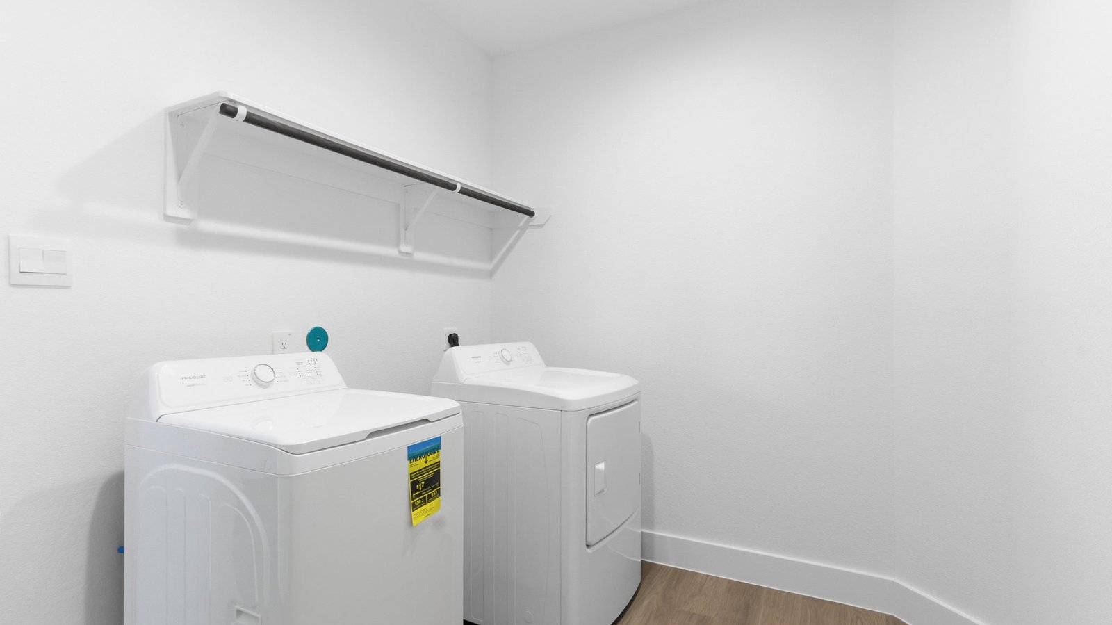 Spacious laundry room with washer and dryer connections, hanging rod, and vinyl wood flooring
