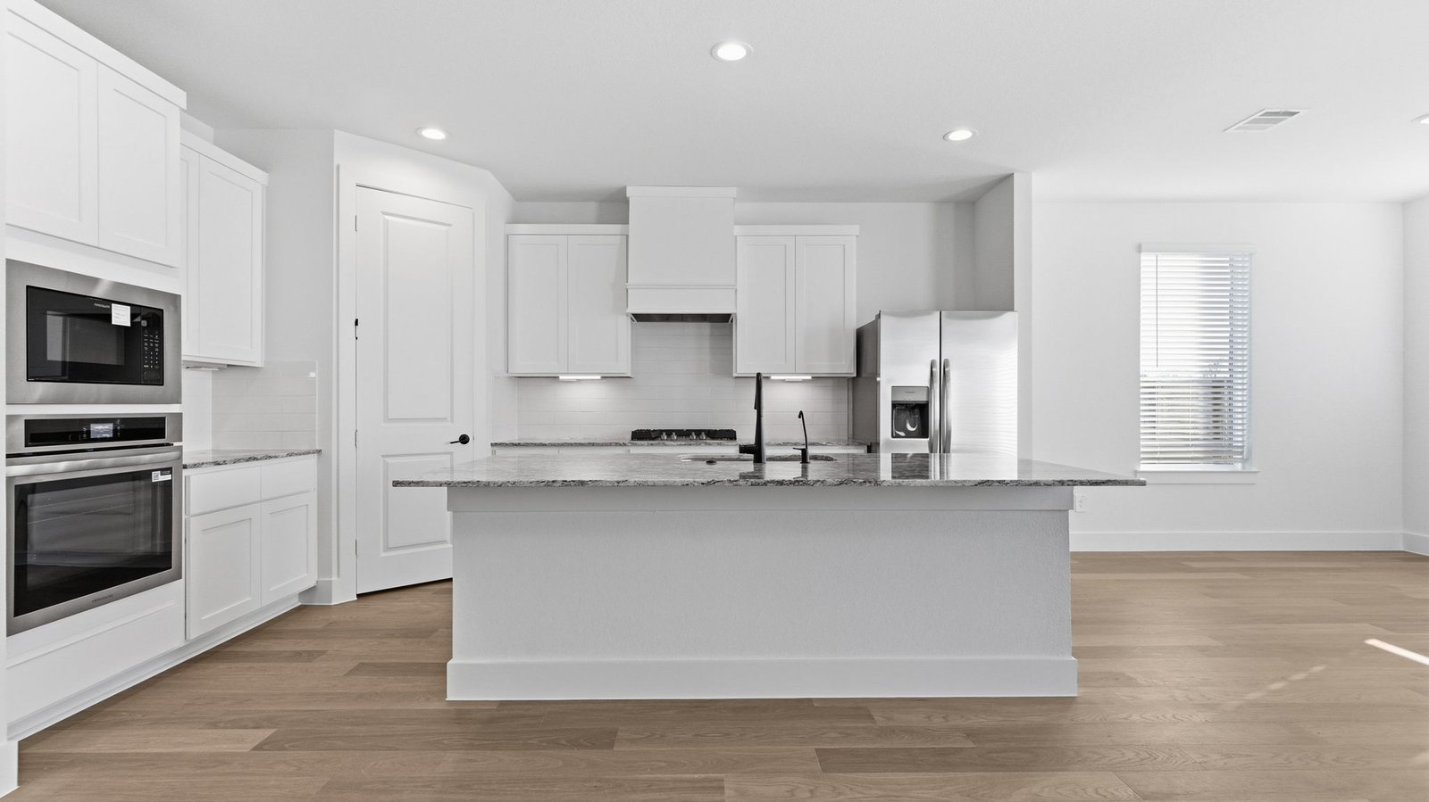 Kitchen adorned with white cabinets seamlessly integrated into an open dining area layout.