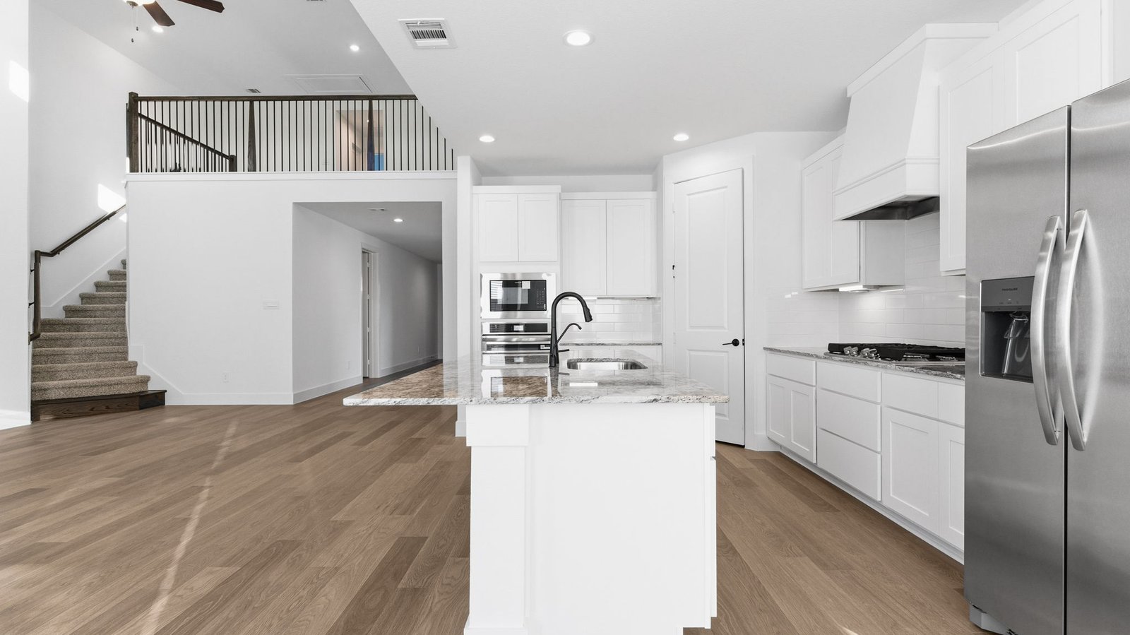 An open concept kitchen with an island with bar seating and access to the living and dining areas.