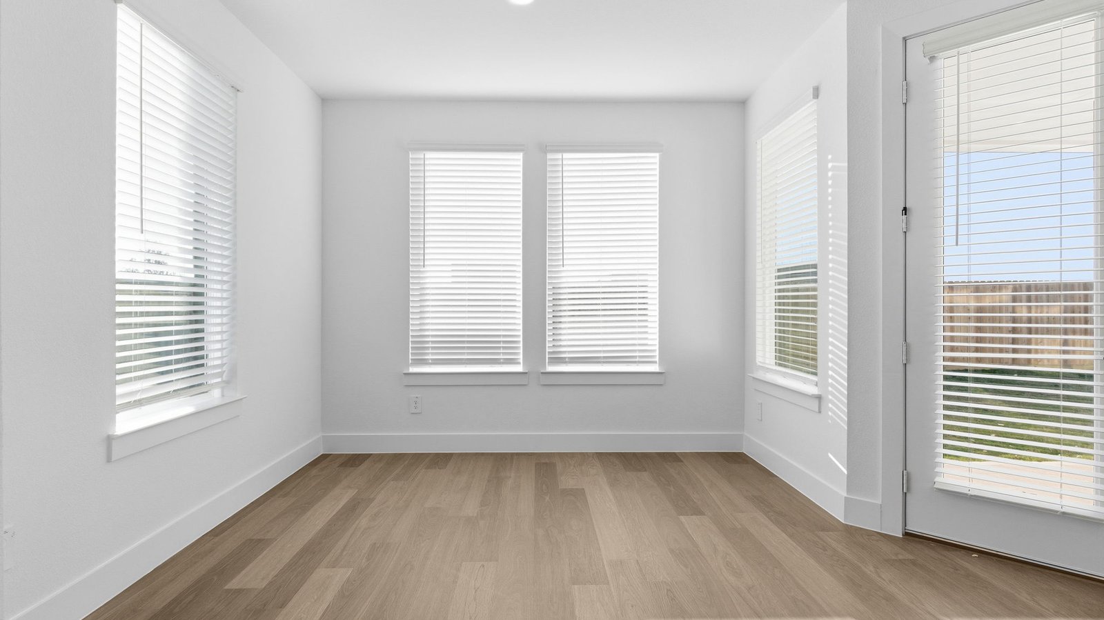 Formal dining room with large windows, wood floors, and view of the backyard.