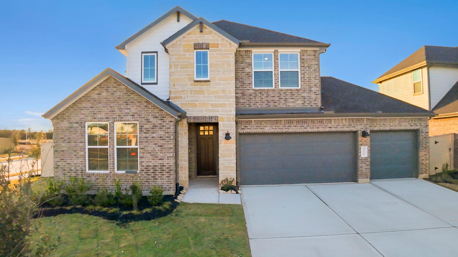 A two-story home with brick and stone exterior with a two-car garage and a well maintained front lawn in league city