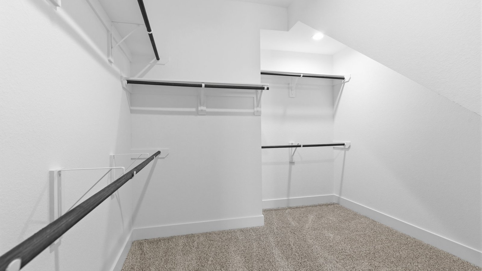 A spacious walk-in closet off the primary bathroom with multiple hanging rods, and shelves for maximum storage capabilities.