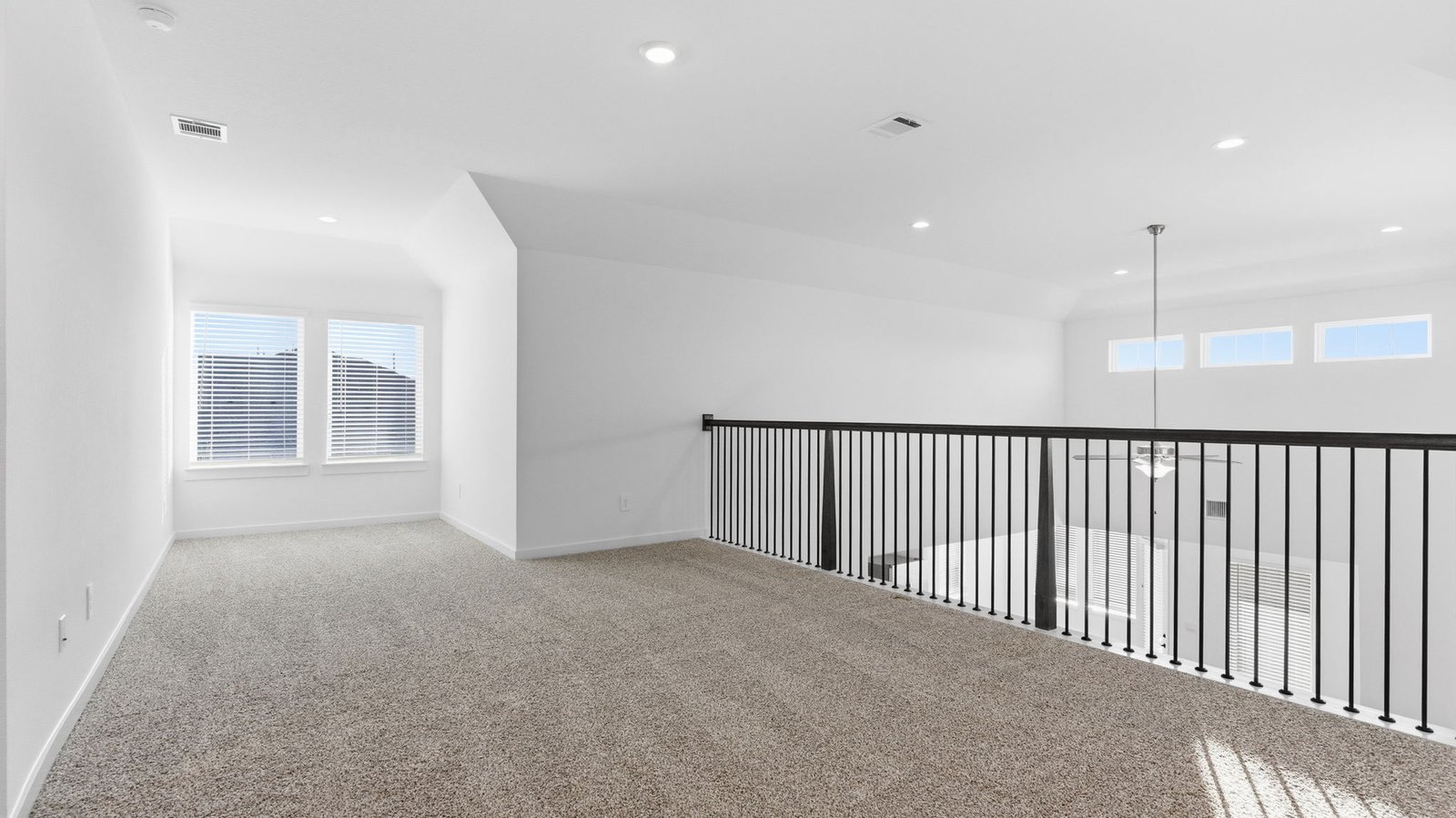 A spacious upstairs living area with plenty of natural light from windows overlooking side of the home