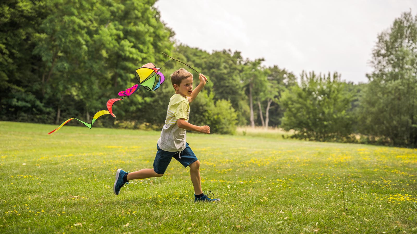 child running in the grassy field with a kite