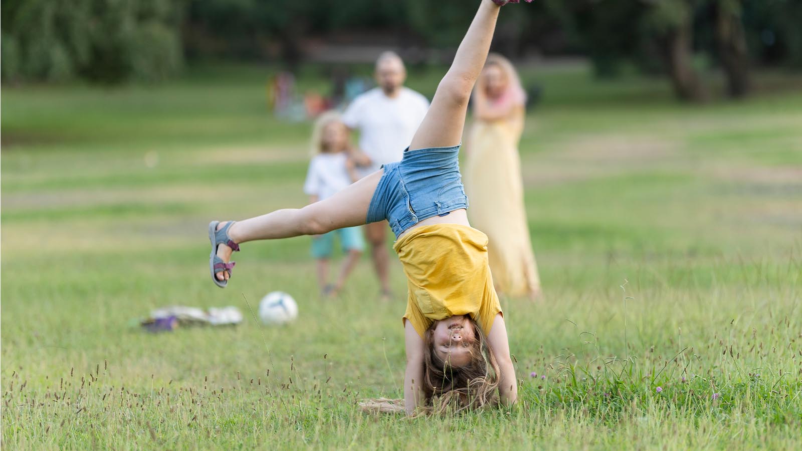 A kid doing a cartwheel in a grassy field