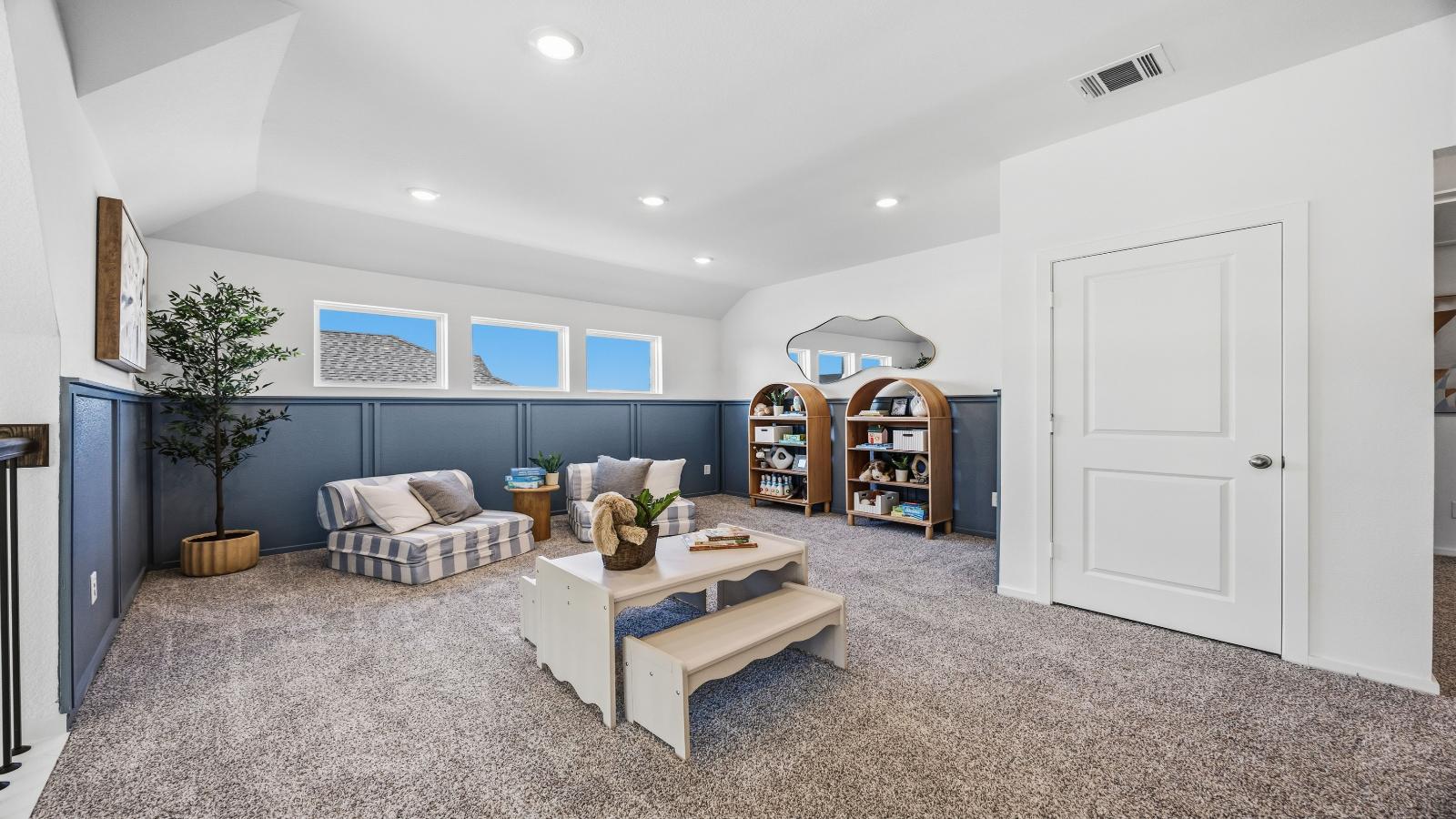 A spacious upstairs living area with plenty of natural light from windows overlooking side of the home