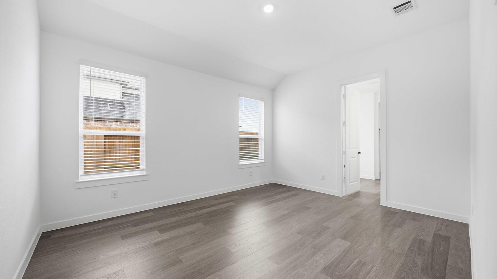 A spacious primary bedroom emphasizing open space and natural lighting with large windows.