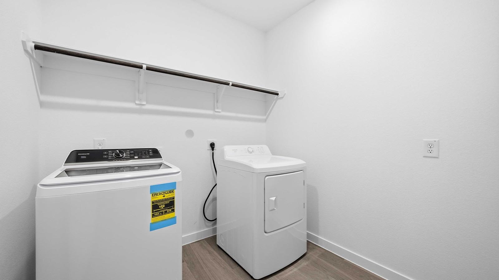 Spacious laundry room with washer and dryer connections, hanging rod, and vinyl wood flooring