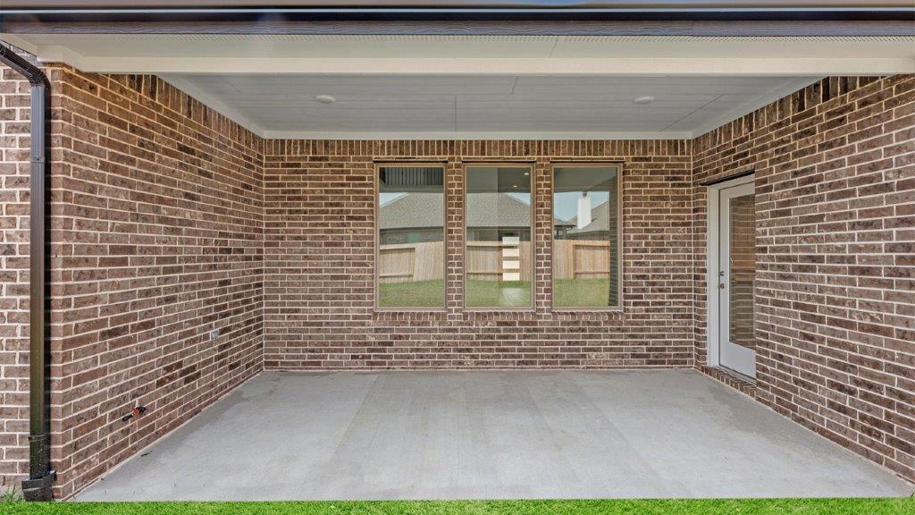 Outdoor covered patio with seating area overlooking a well-maintained lawn, perfect for relaxation.