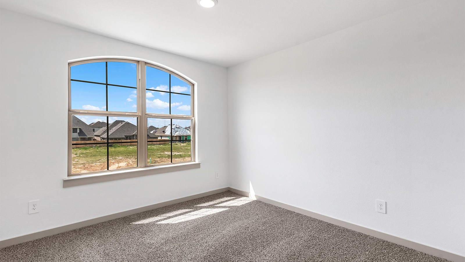 A bedroom shown as an at home office with a bright window allowing natural light to enter.
