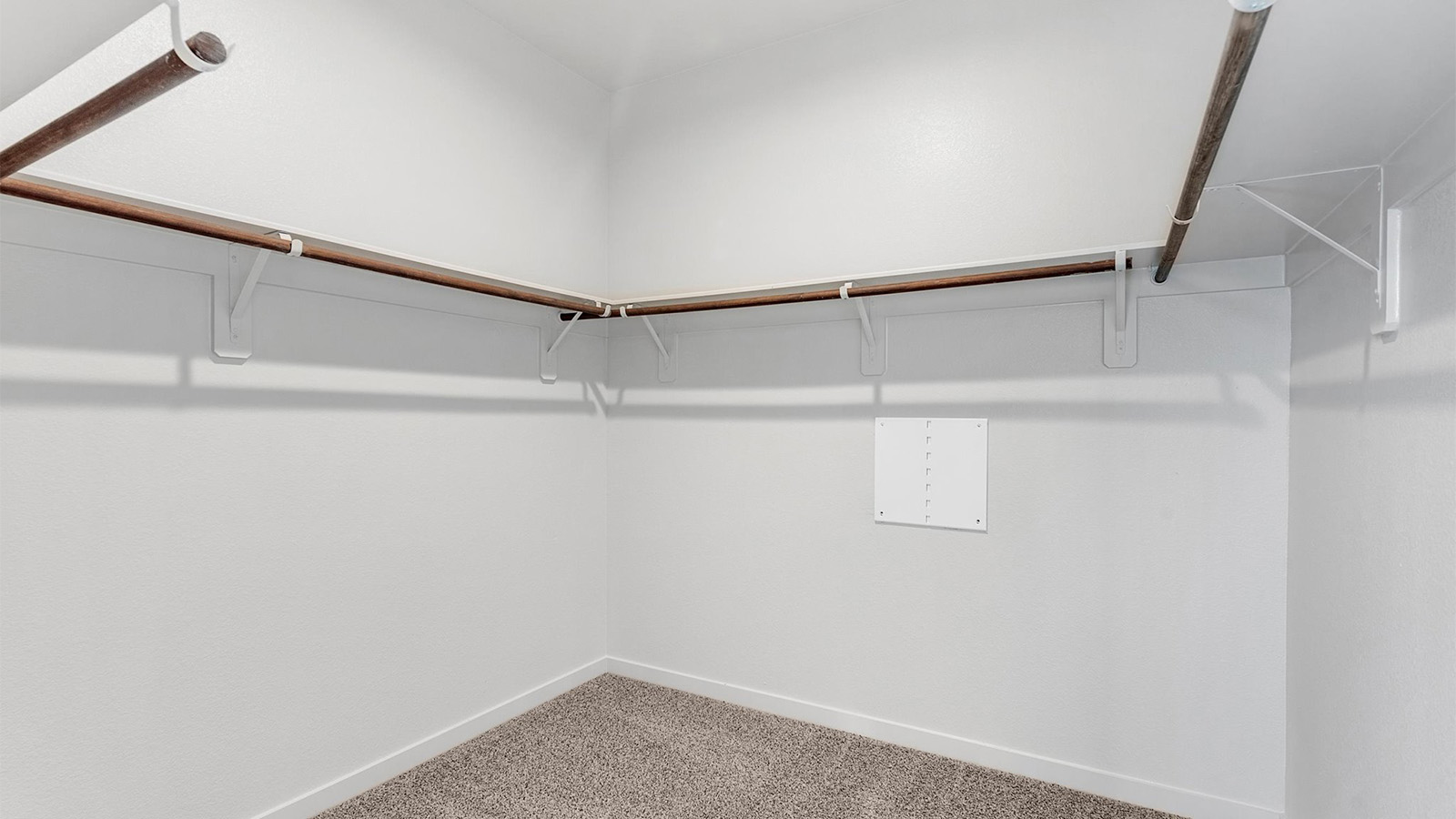 A spacious walk-in closet off the primary bathroom with multiple hanging rods, and shelves for maximum storage capabilities.