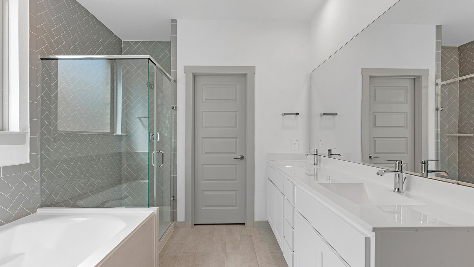 Modern primary bathroom with double vanities, quartz countertops, and a glass-enclosed shower with a walk-in closet.