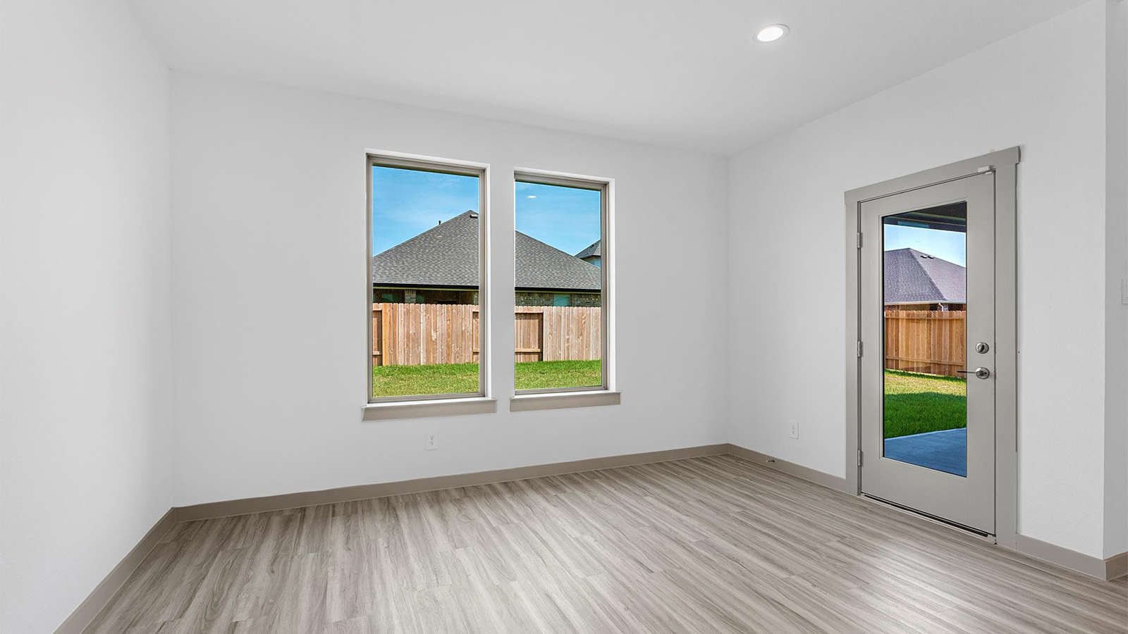 Formal dining room with large windows, vinyl wood floors, and view of the backyard.