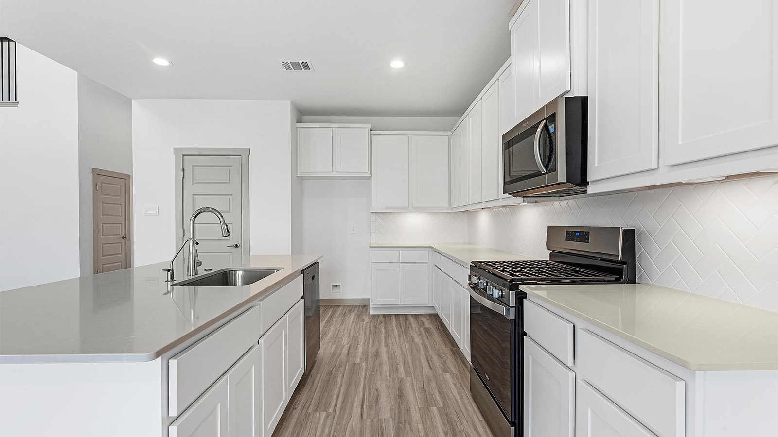 Bright and spacious kitchen with quartz countertops, stainless steel appliances, and an island with bar seating.