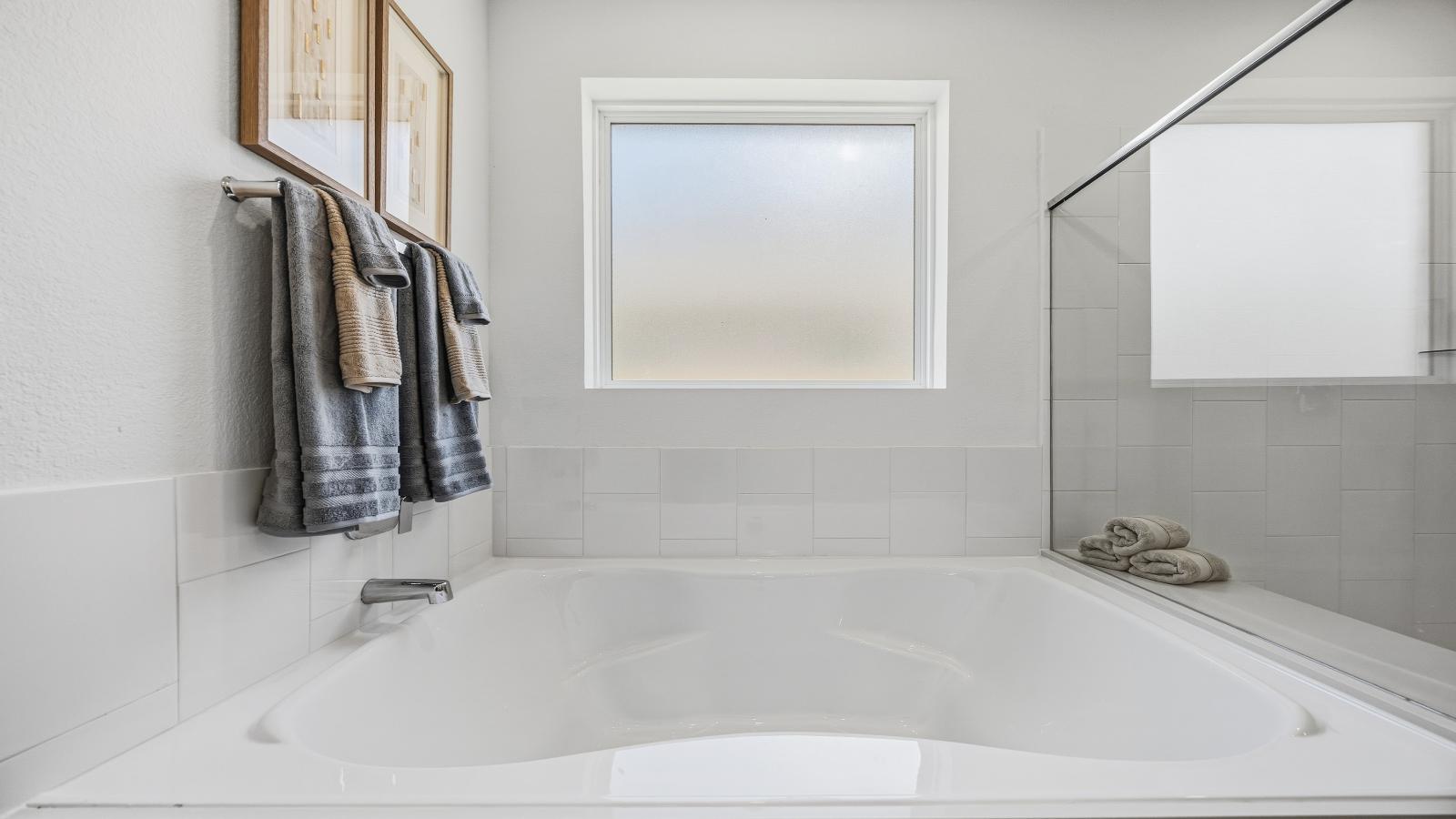 Primary bathroom with a glass-enclosed standing shower and separate soaking tub.