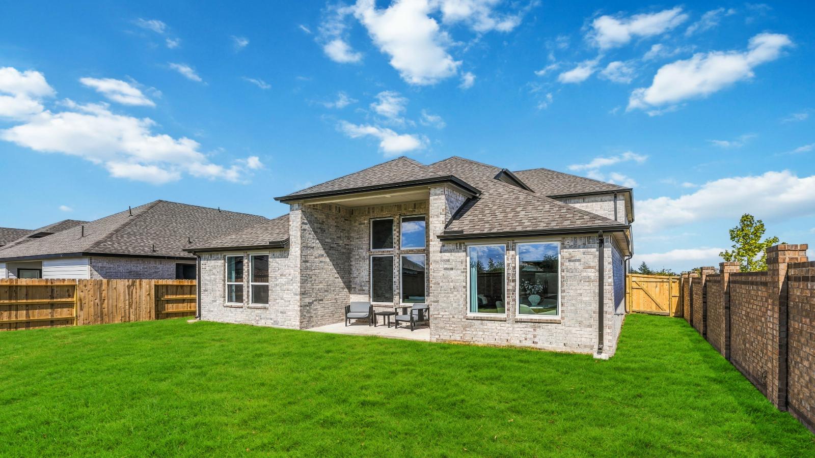 Outdoor covered patio with seating area overlooking a well-maintained lawn, perfect for relaxation.