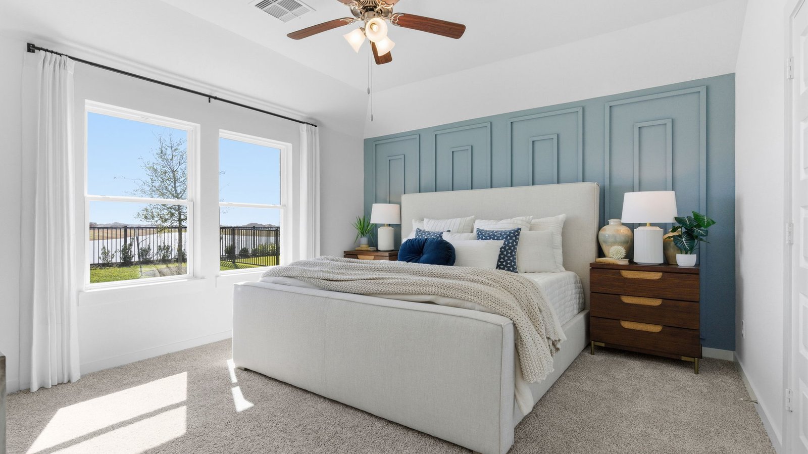 Primary bedroom with ceiling fan, plush carpeting, and a large walk-in closet.