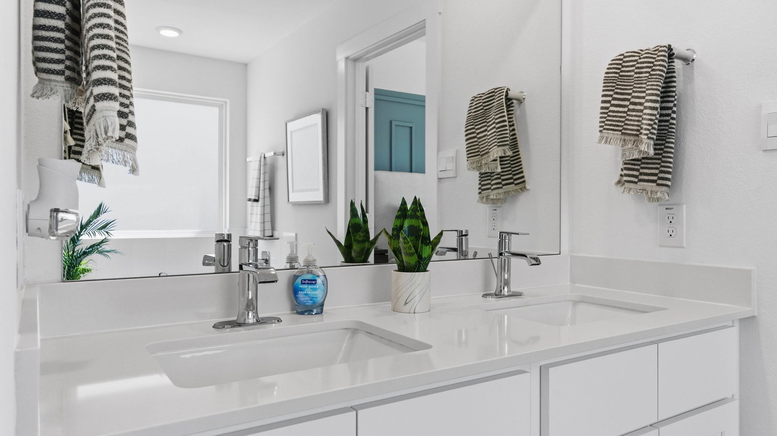 Modern primary bathroom with double vanities, granite countertops, and a glass-enclosed shower with a walk-in closet.
