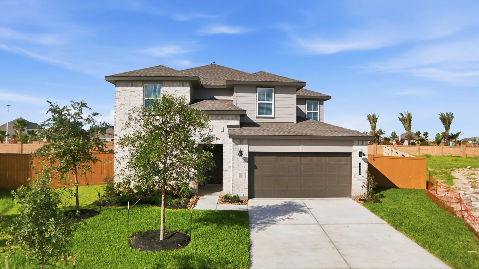 A two-story home with brick and stone exterior with a two-car garage and a well-maintained front lawn in texas city