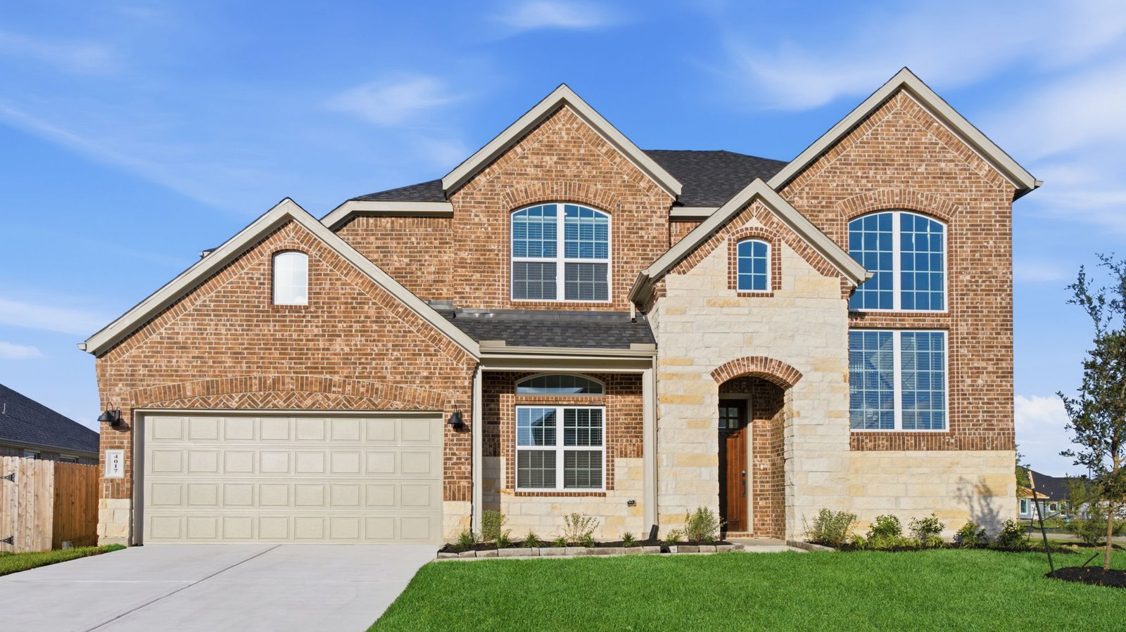 Newly built two story home with traditional architecture, a garage, and landscaped front yard.