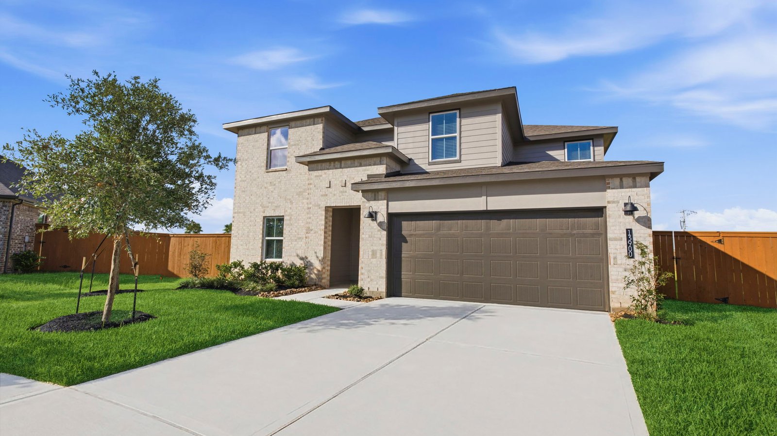 A two-story home with brick and stone exterior with a two-car garage and a well maintained front lawn in texas city