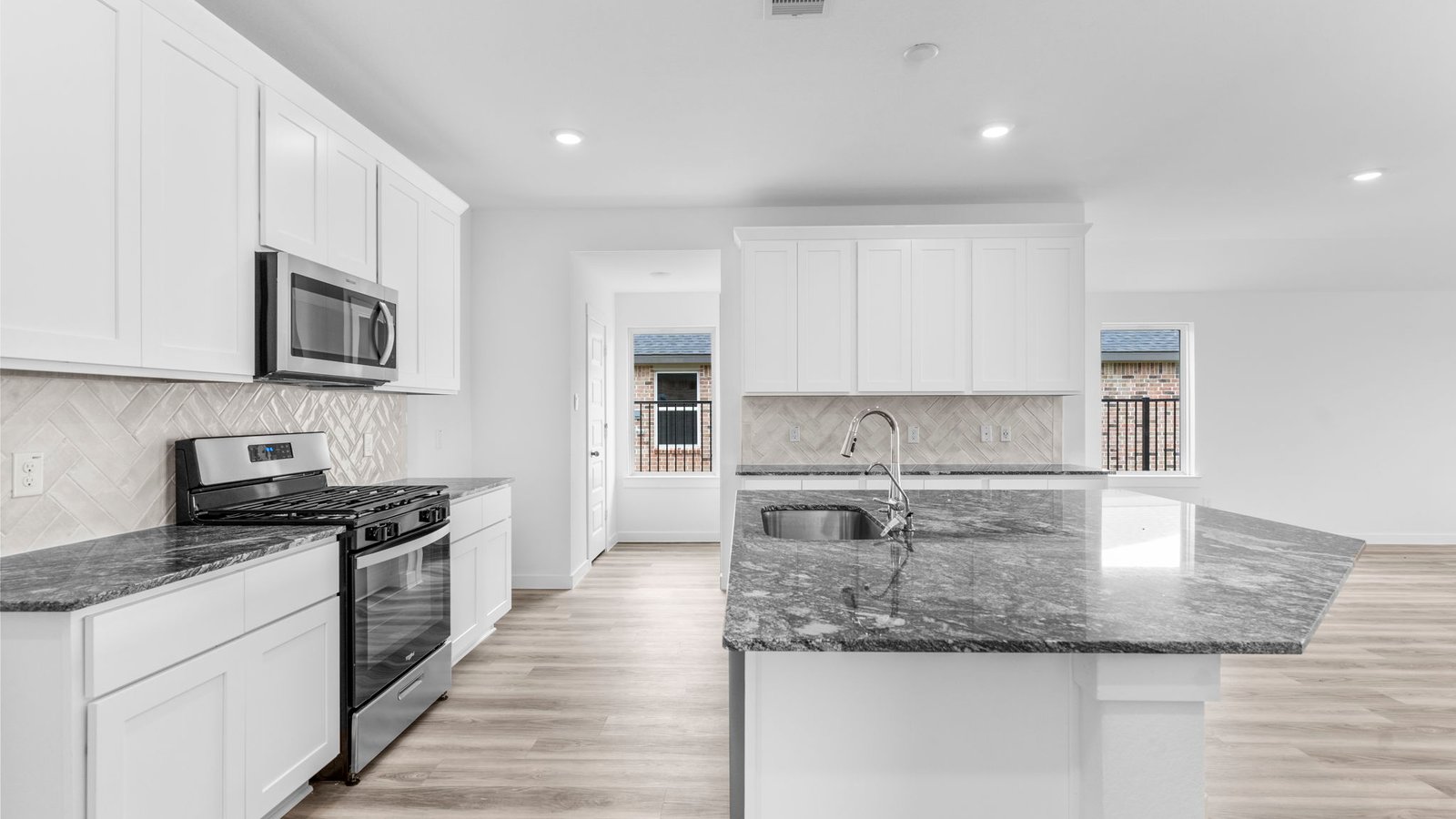 Bright and spacious kitchen with quartz countertops, stainless steel appliances, and an island with bar seating.