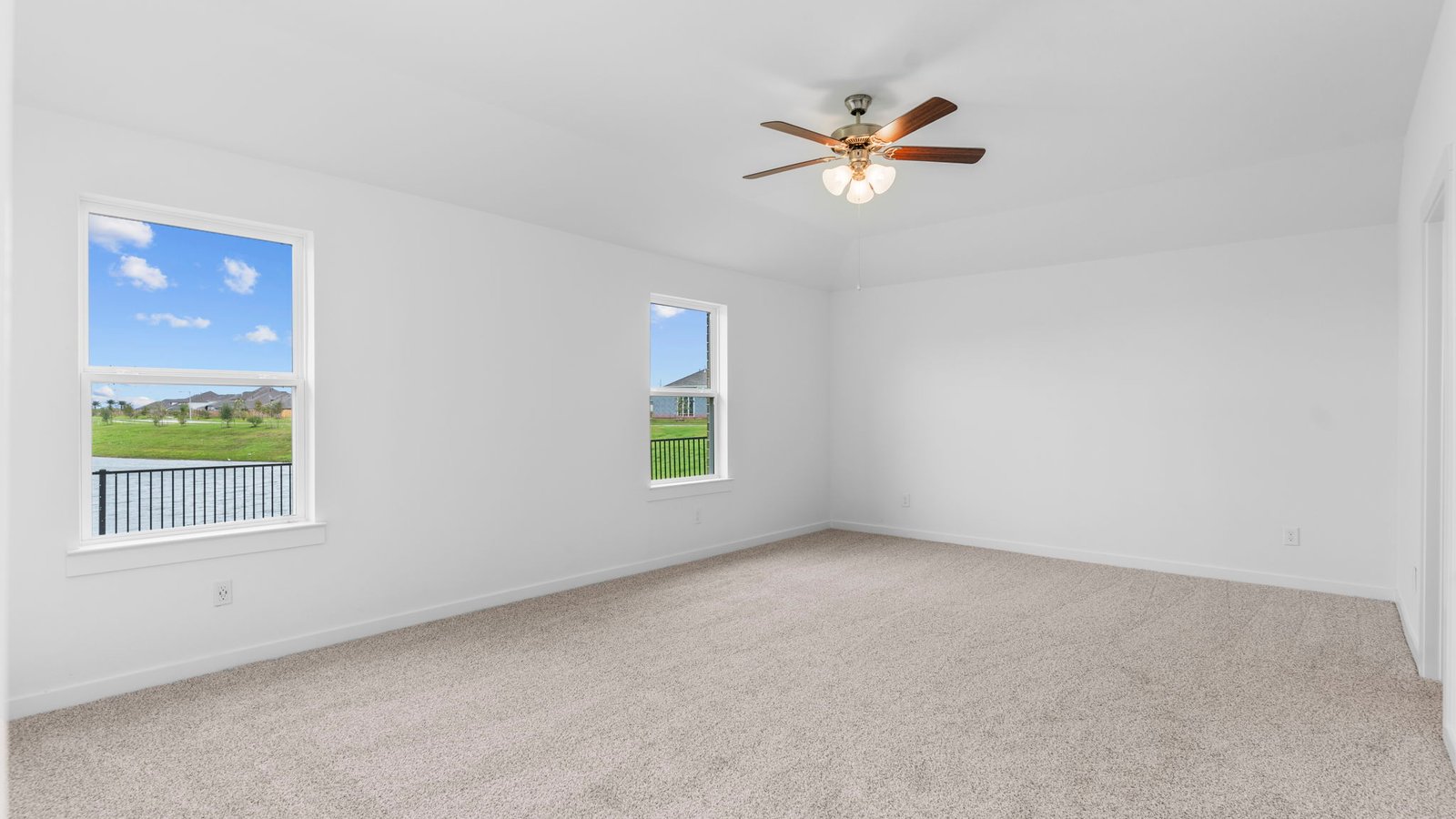 Primary bedroom with ceiling fan, plush carpeting, and a large walk-in closet.