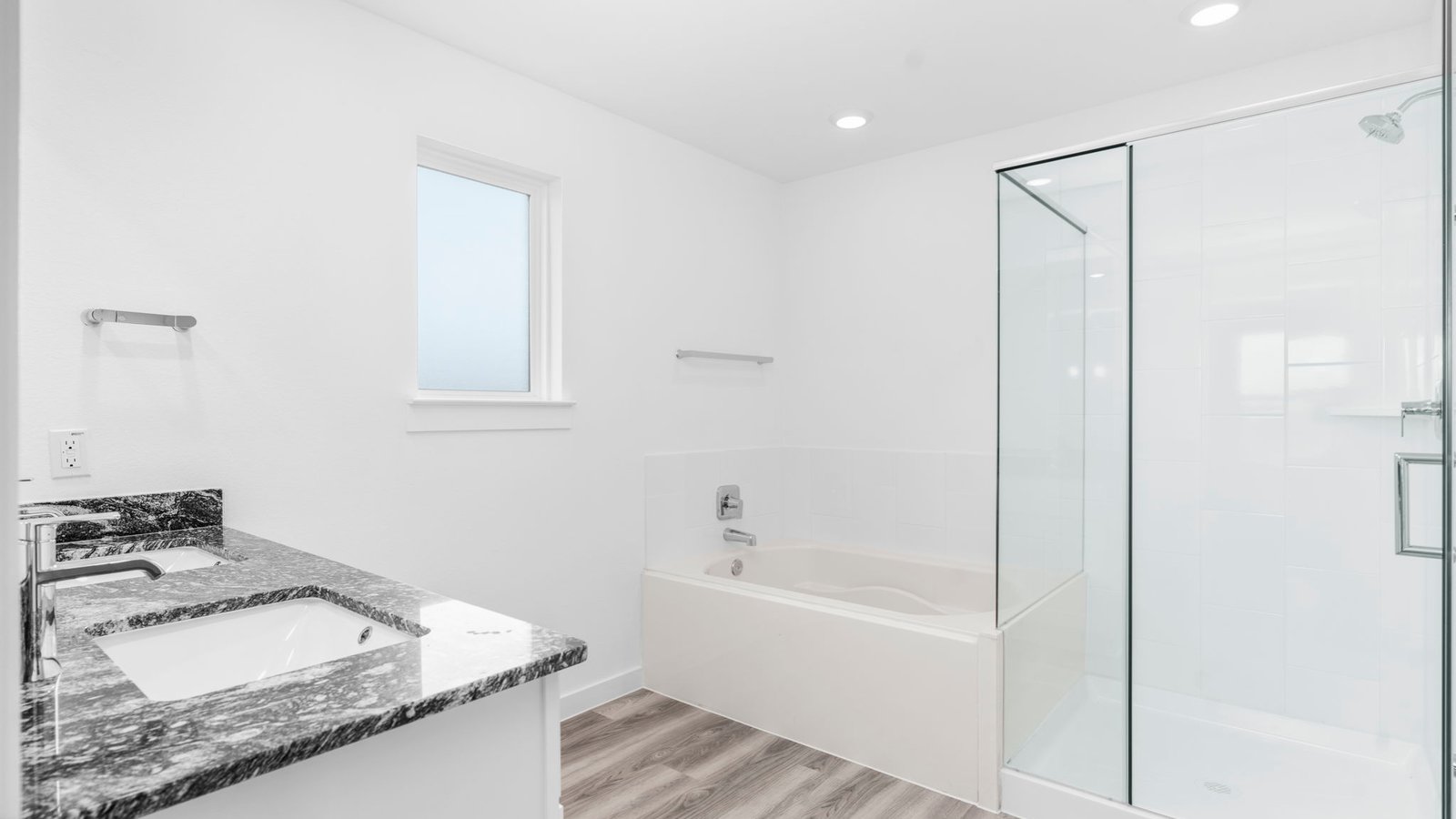 Modern primary bathroom with double vanities, quartz countertops, and a glass-enclosed shower with a walk-in closet.
