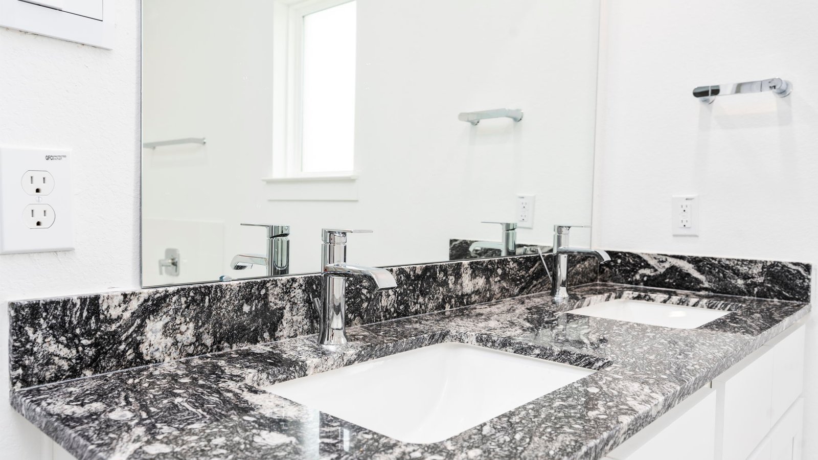 Modern primary bathroom with double vanities, quartz countertops, and a glass-enclosed shower with a walk-in closet.