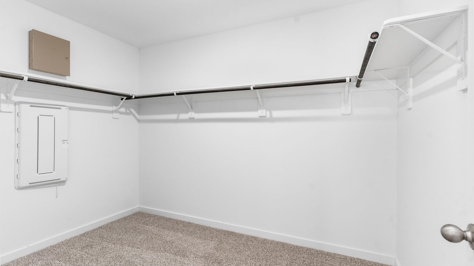 A spacious walk-in closet off the primary bathroom with multiple hanging rods, and shelves for maximum storage capabilities.