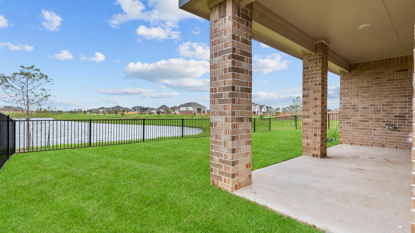 Outdoor covered patio with seating area overlooking a well-maintained lawn, perfect for relaxation.