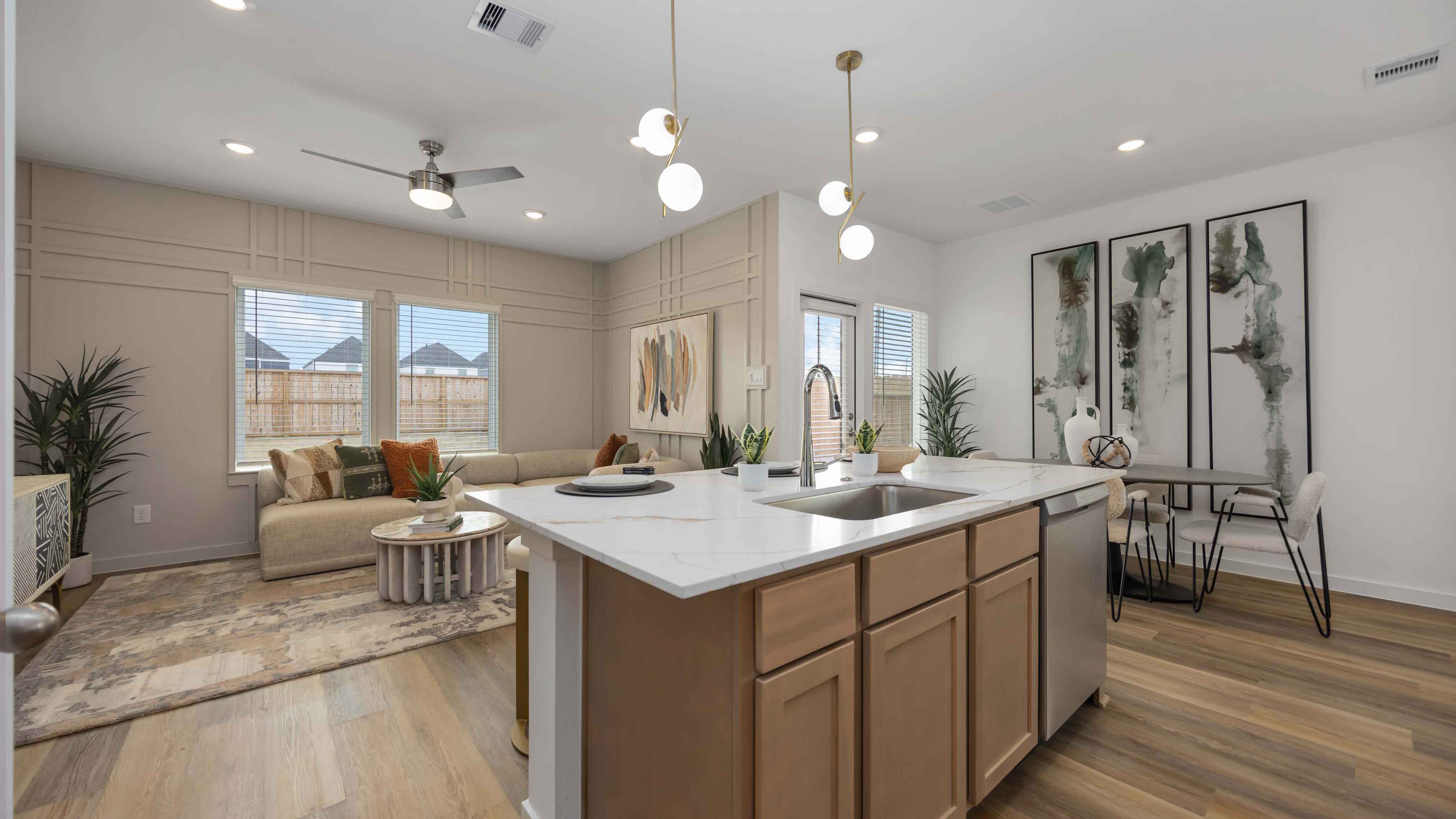 beautiful new kitchen with quartz counters, light grey cabinets, and herringbone backsplash
